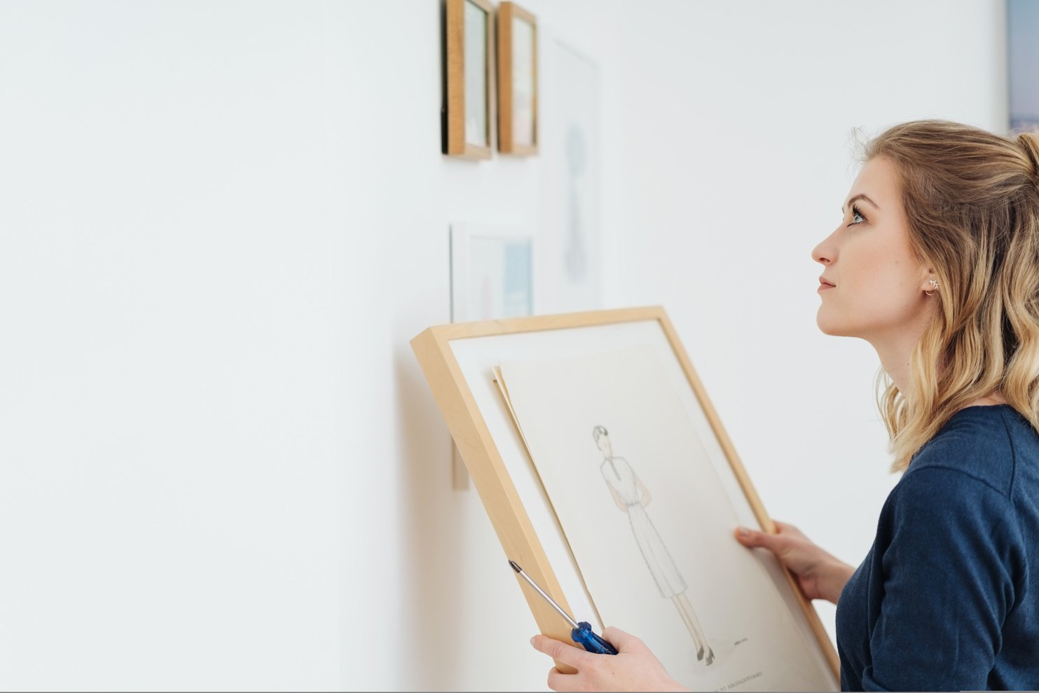 Young woman contemplating where to hang a picture